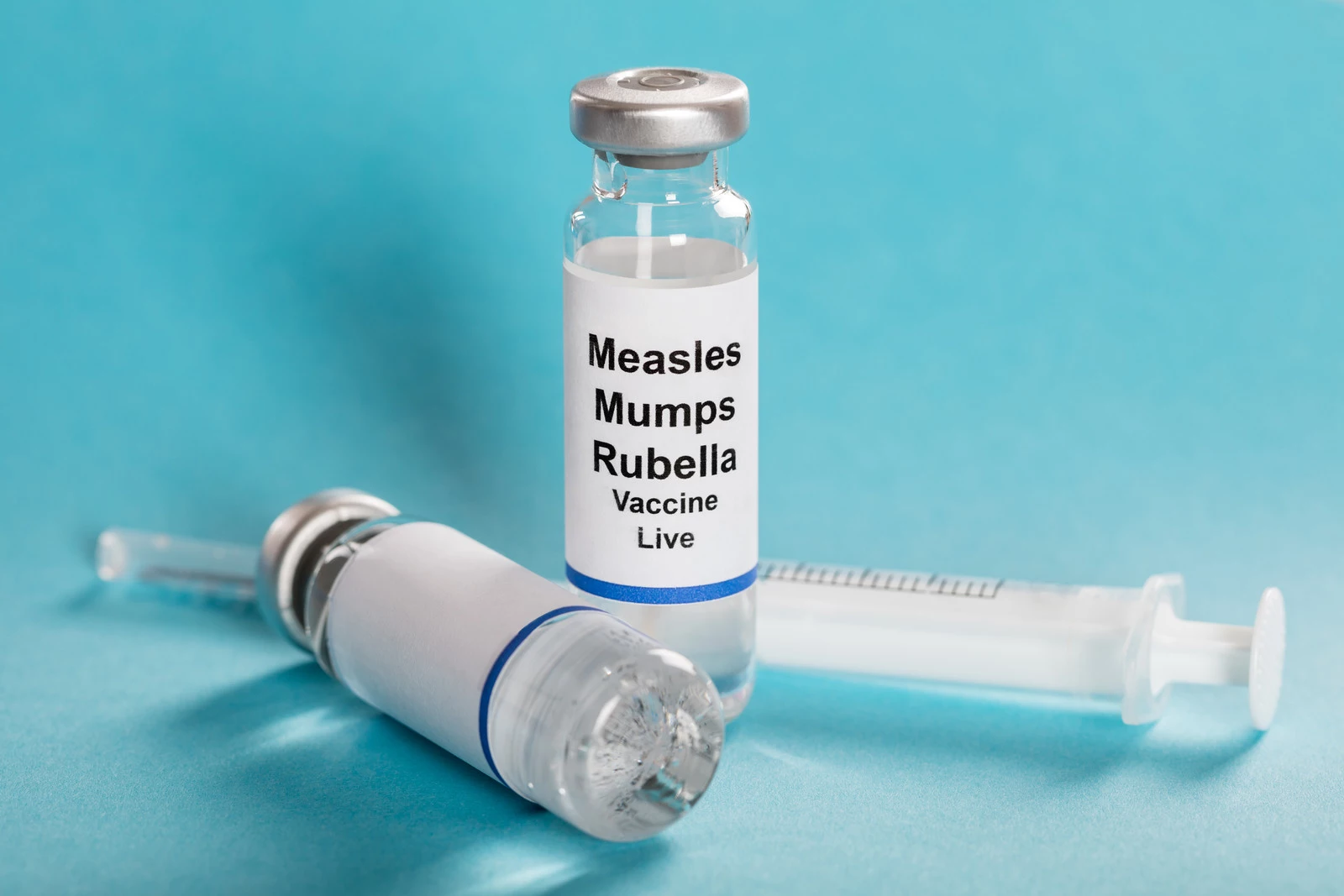 Measles Mumps Rubella Vaccine Vials With Syringe Over Turquoise Background